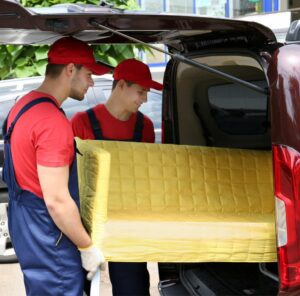 Günstig umziehen in Gießen: Umzugshelfer laden ein gelbes Sofa in einen Transporter