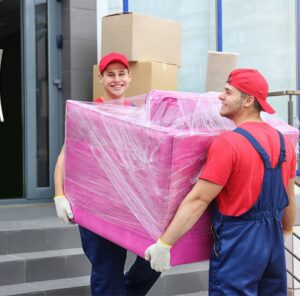 Zwei Umzugshelfer tragen ein in Folie gepacktes Möbelstück – Umzug in Gießen