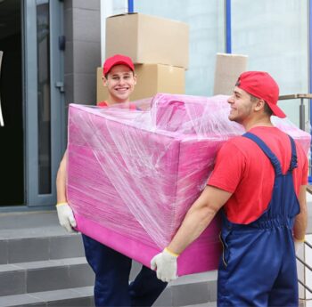 Zwei Umzugshelfer tragen ein in Folie gepacktes Möbelstück – Umzug in Gießen
