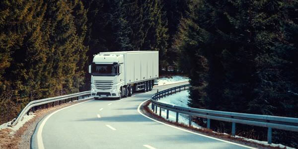 Klaviertransport Gießen: Lkw fährt auf einer kurvigen Straße durch den Wald