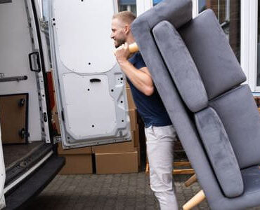 Möbellift Gießen: Helfer tragen ein graues Sofa aus einem Transporter